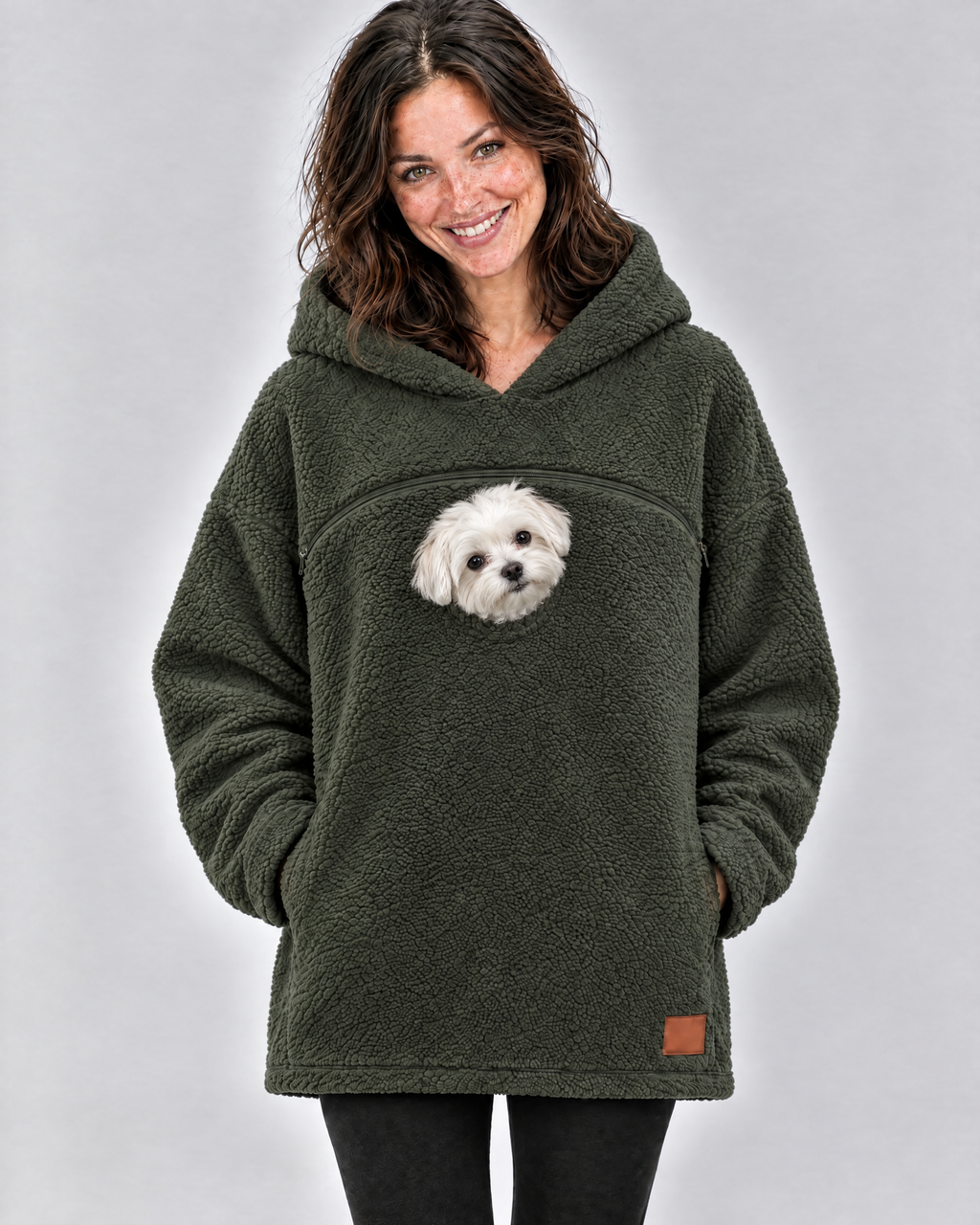 Woman laughing in an army green pouch hoodie with a small white Maltese peeking out below the chest zipper