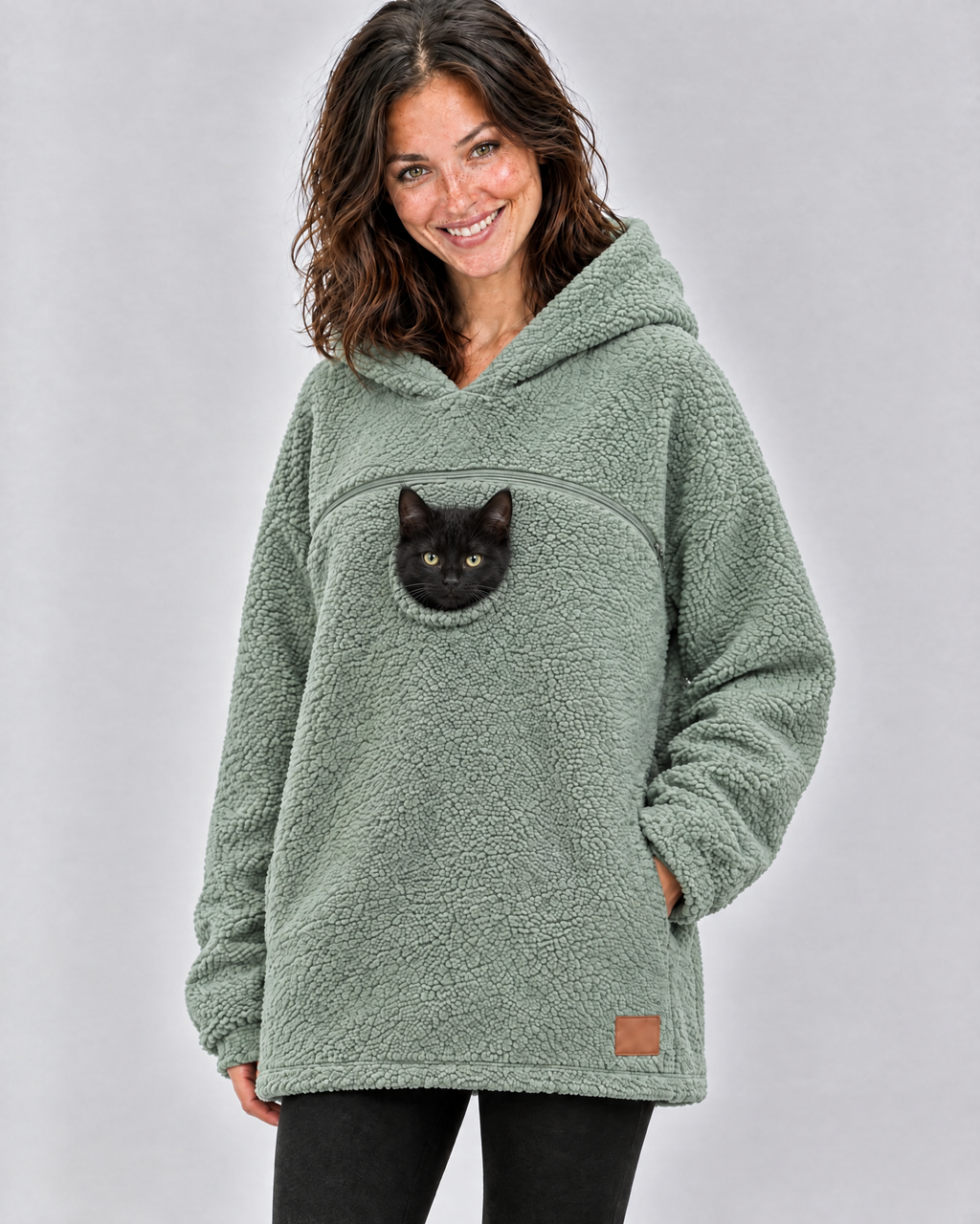 Woman in a mint green pouch hoodie with a black kitten peeking out of the chest opening