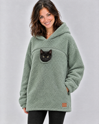 Woman in a mint green pouch hoodie with a black kitten peeking out of the chest opening